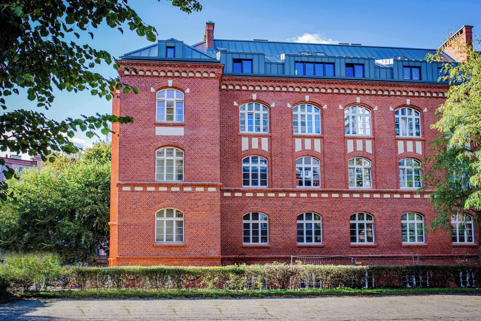 A charming brick building surrounded by greenery, highlighting the historic yet modern character of the area.