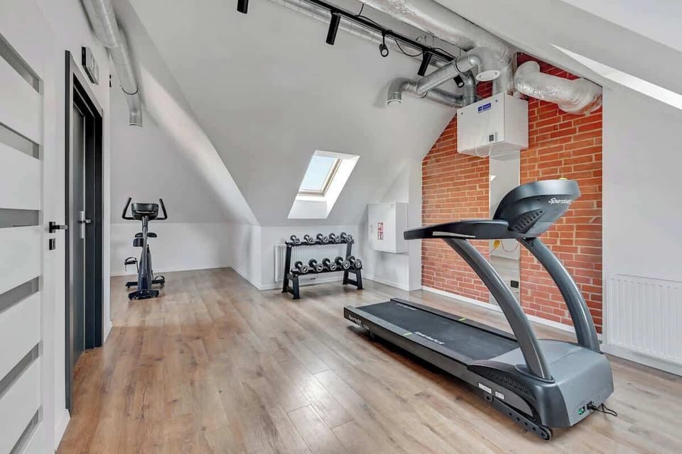 Gym combines fitness equipment with the raw charm of exposed brick walls, creating a dynamic, sleek, and energizing atmosphere perfect for both workouts and relaxation.