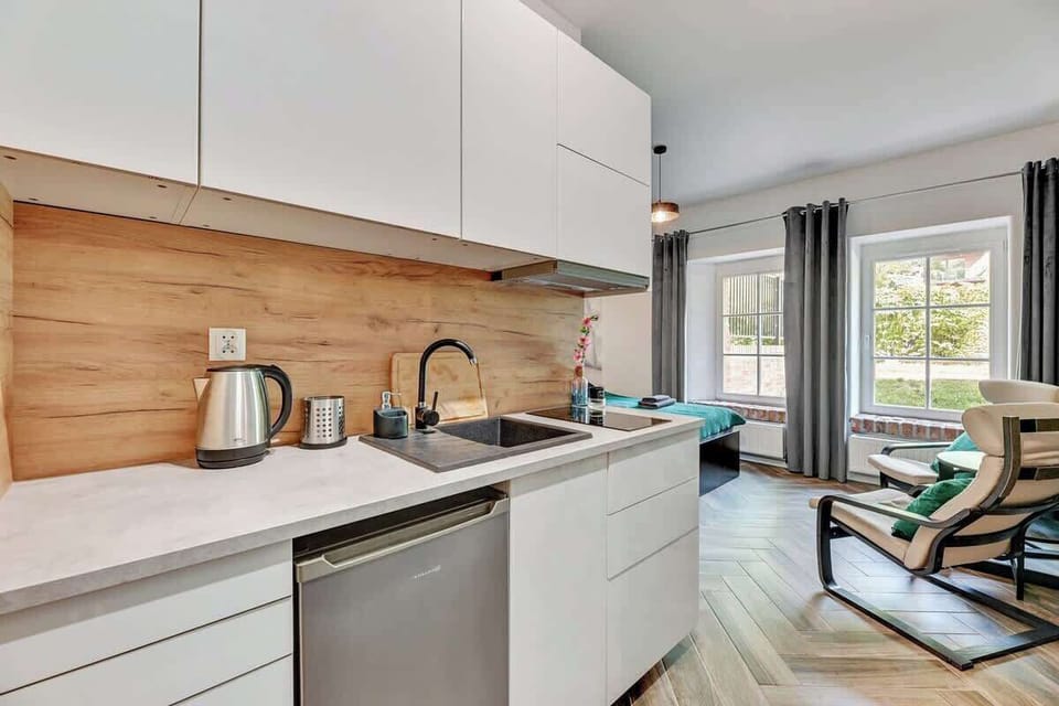 Chic blend of white and wood accents, complemented by cozy armchairs and large windows that fill the space with light, creating a warm and inviting atmosphere.