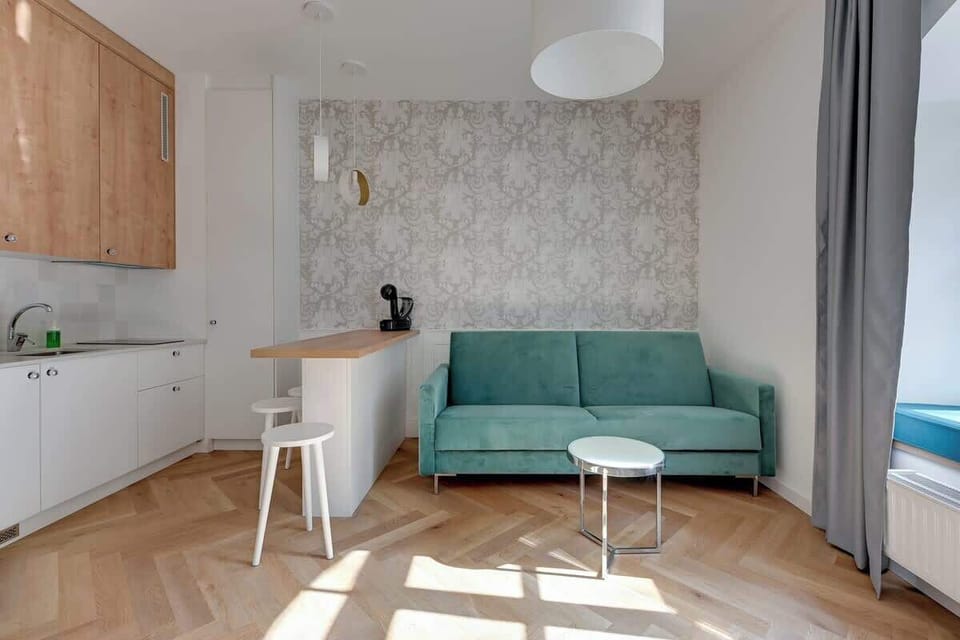Chic, plush teal sofa, minimalist white furnishings, and a striking patterned wallpaper, all bathed in natural light