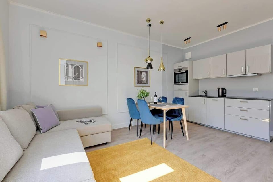 A modern kitchen with light-colored cabinets, a large countertop, stylish lighting, and an organized cooking space