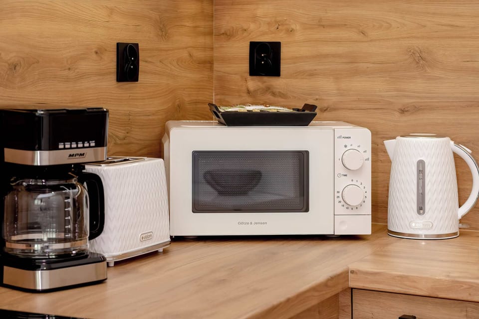Close-up of the wooden countertop where the microwave, electric kettle, toaster and coffee machine are located.