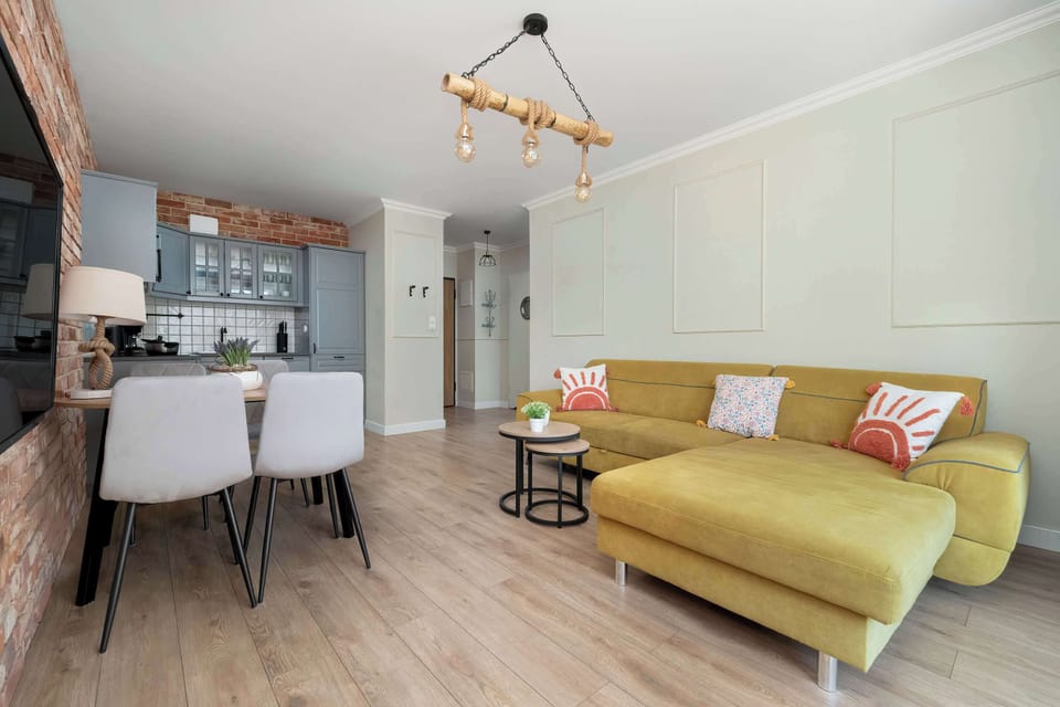 Living room with a corner sofa bed, coffee table, kitchenette and table with chairs.