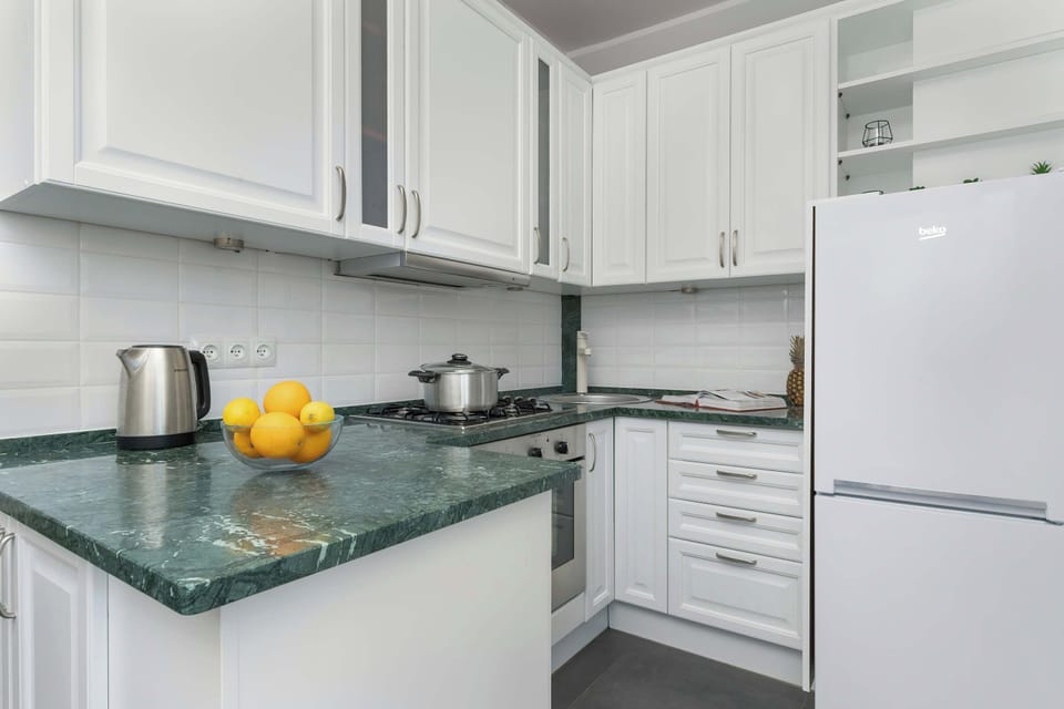 A view of the kitchen with a green countertop, clean white cabinetry, and modern design.