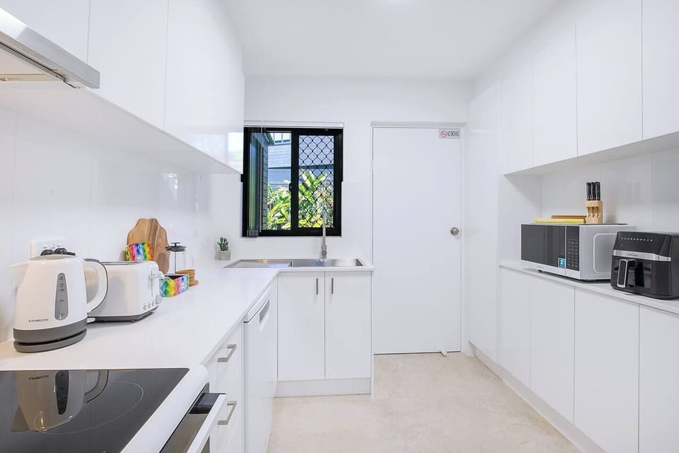 Prepare meals in the fully equipped kitchen, designed with ample bench space and modern appliances including an oven, stove, microwave, dishwasher, air fryer, and French press for morning coffee rituals.
