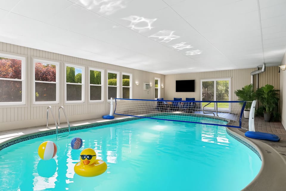 Play and unwind in your private indoor pool room with a volleyball net, floaties, lounge area, and smart TV.
