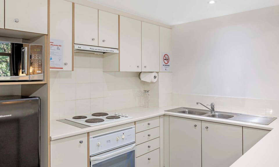 Kitchen with electric cooktop, oven, sink, and ample cabinetry.