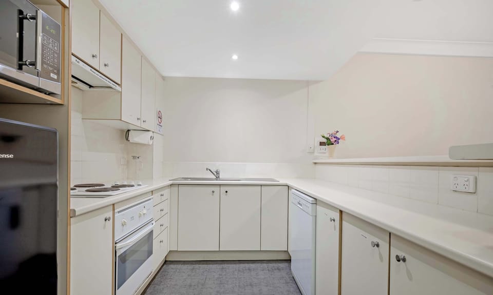 Fully equipped kitchen with ample cabinetry, cooktop, oven, and preparation space.