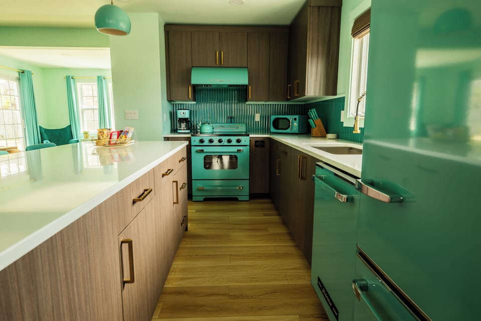 Vintage-inspired kitchen with teal appliances and wood cabinetry.