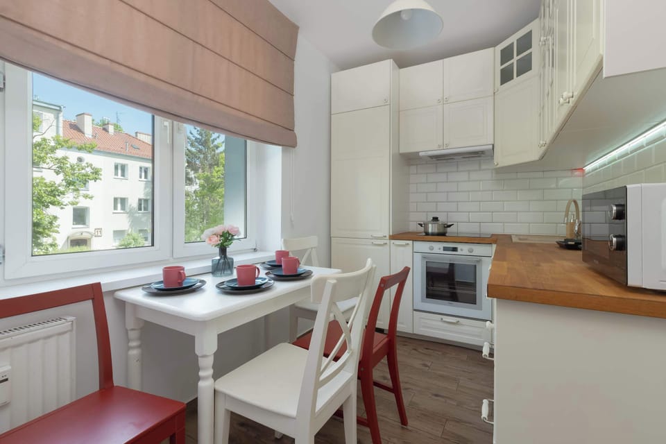 A modern kitchen and dining area with white cabinetry, wooden countertops, and a window-side table set for four.
