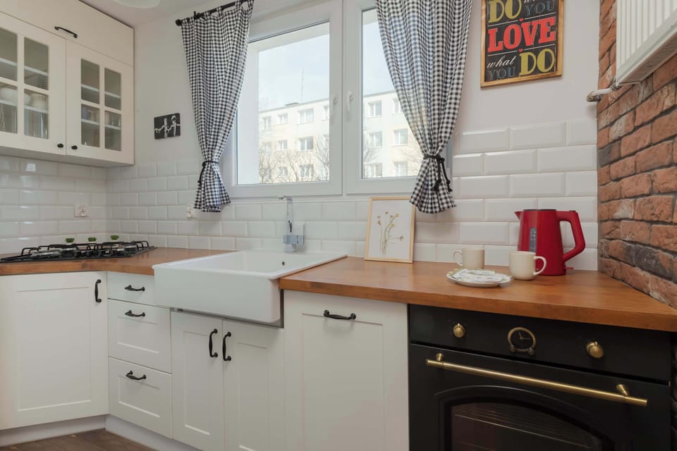 A charming kitchen with a vintage-style oven, white cabinetry, and rustic brick accents around the window.