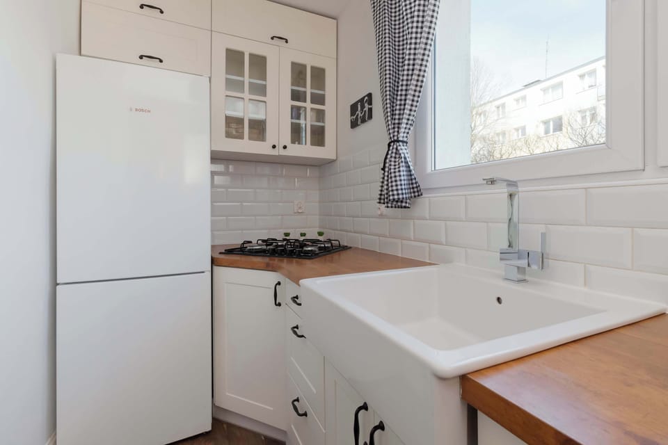 A compact yet functional kitchen equipped with white appliances, charming wooden countertops, and bright windows for natural light.