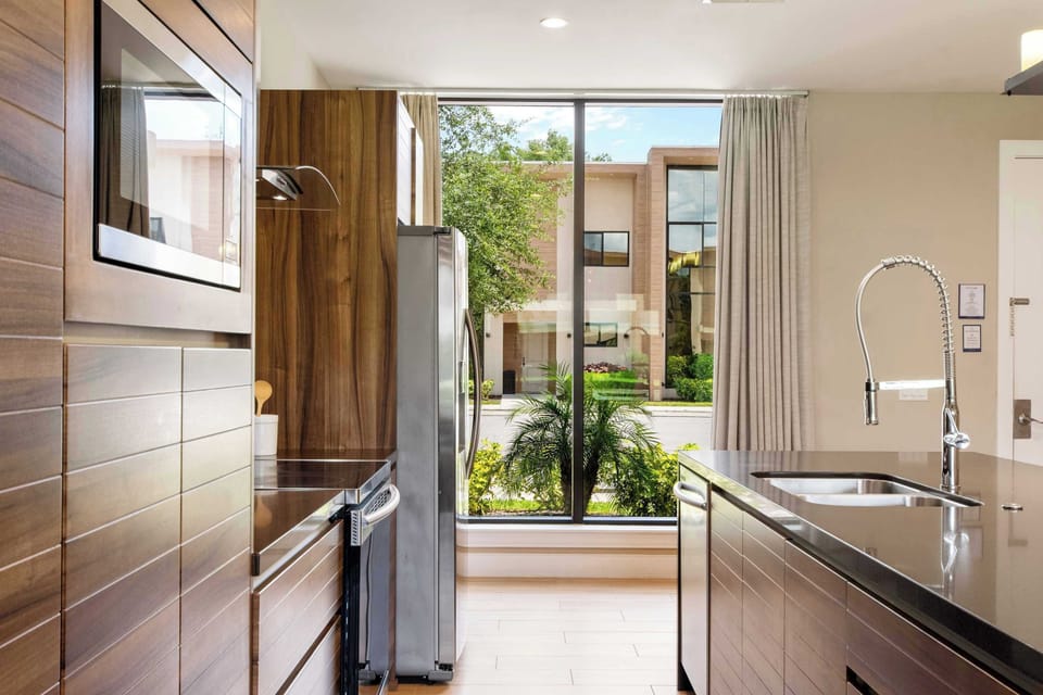 Sleek modern kitchen with rich wood grain and a sunlit garden view.