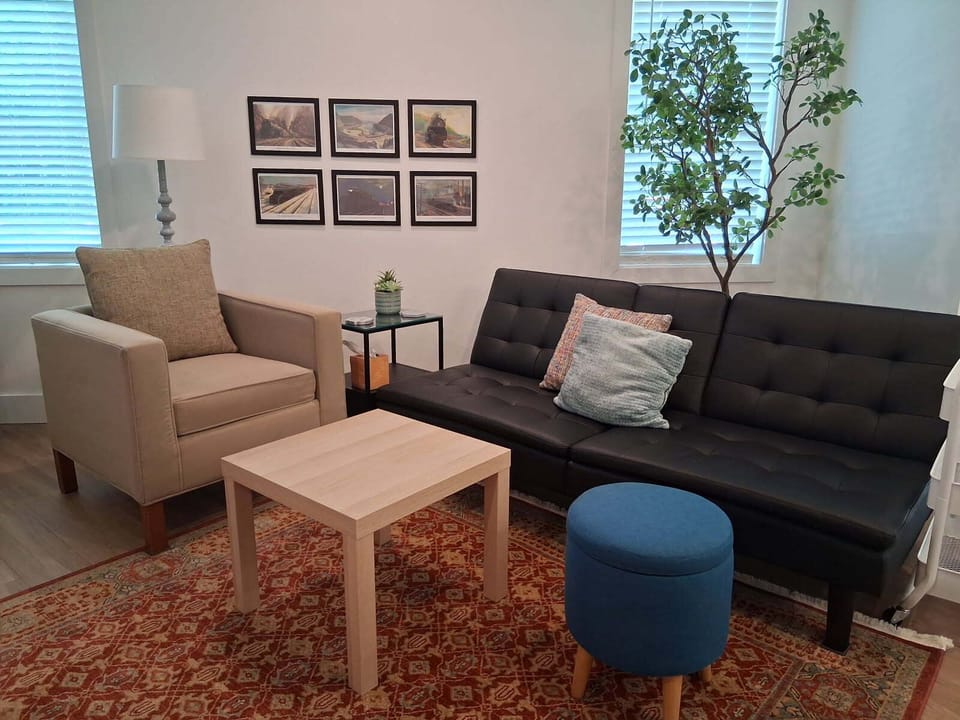 Living area with sofa bed, 2 arm chairs, smart TV and stand