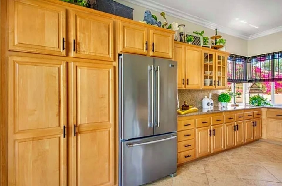 Modern kitchen with stainless fridge and warm wood cabinetry.