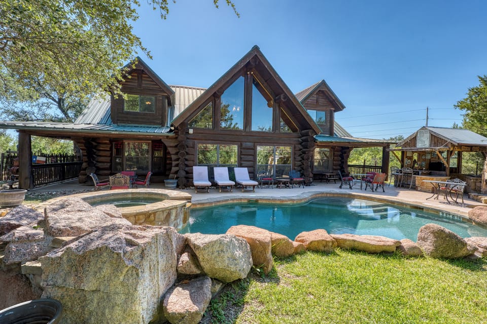 Beautiful log cabin retreat featuring a sparkling rock-lined pool, relaxing lounge chairs, and serene wooded surroundings