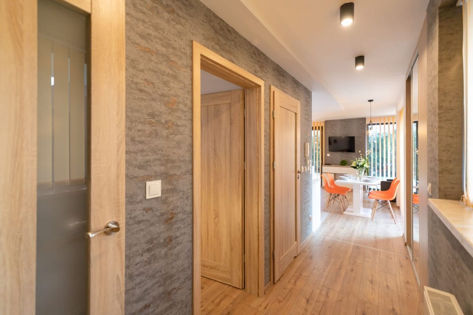 Hallway with wooden doors, light flooring, and modern lighting.