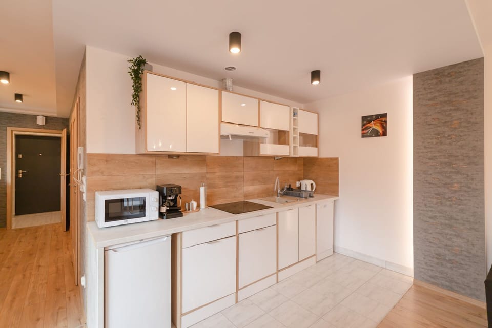 White modern kitchen with built-in appliances and wooden accents.