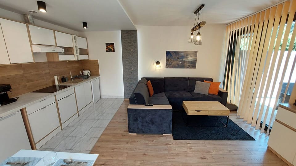 Living room and kitchenette with modern white cabinets and gray sofa.
