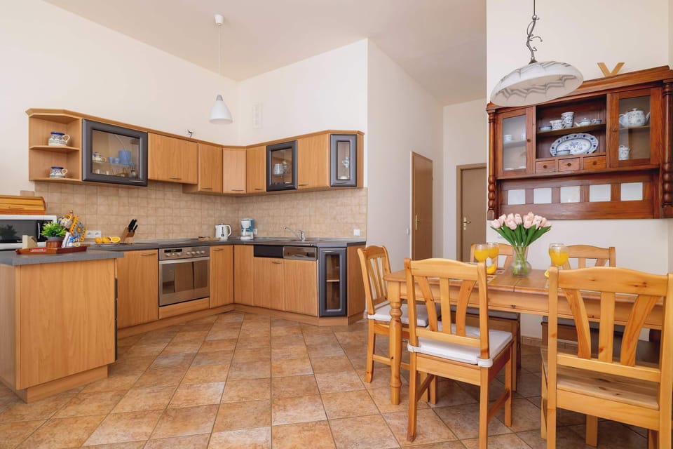 Fully equipped kitchenette with electric cooktop, oven, microwave, refrigerator with freezer, dishwasher, electric kettle, coffee maker and dining area.