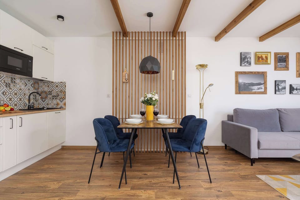 A dining area with navy blue velvet chairs, a round table set for meals, and minimalist wall décor.
