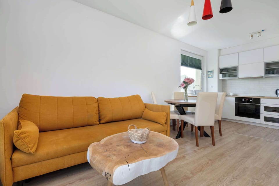 Living room with a sofa, coffee table, TV and kitchenette with dining area.