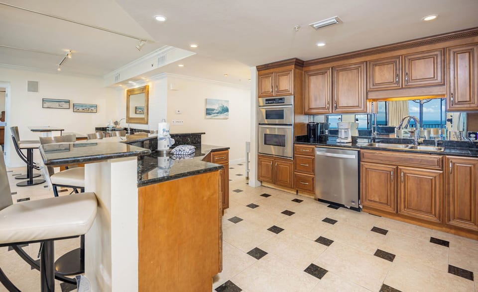 Prepare meals in the spacious kitchen with elegant wooden cabinetry, sleek countertops, and ample seating for socializing