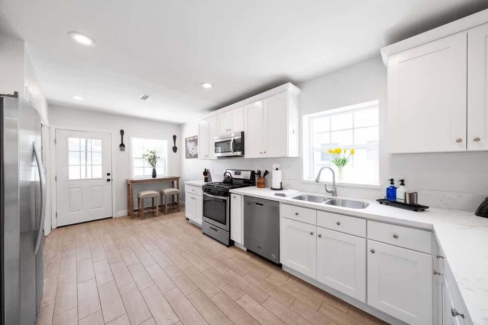 Bright kitchen with white cabinets, sleek appliances, and warm wood flooring