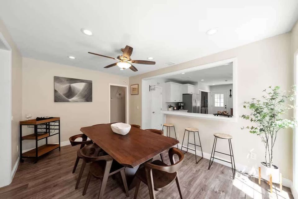 Stylish dining room with wine cart, fan, and open access to kitchen counter.