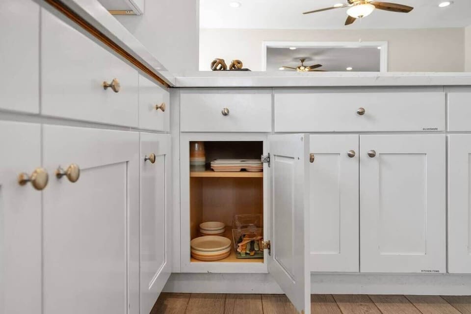 Modern cabinet reveals tidy shelves with dishes and trays for guest cooking ease.