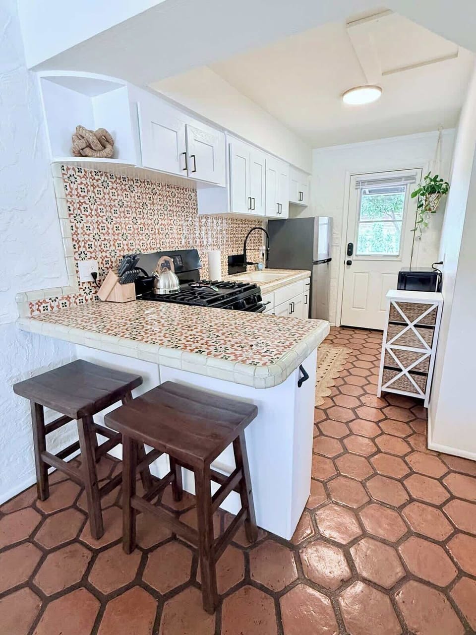Colorful and welcoming, this kitchen features a Talavera tile breakfast bar with rustic wood stools. Whether you're whipping up a quick bite or skipping takeout for a night in, it's stocked with everything you need.