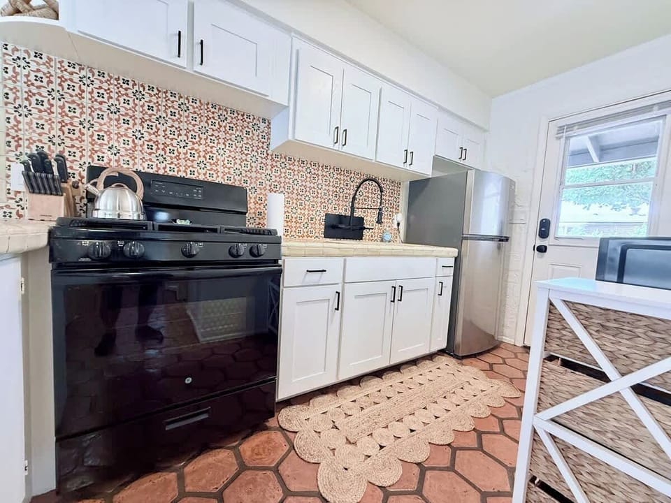 Charming kitchen with hand painted Talavera tile backsplash, white shaker cabinets, and Saltillo floors. Includes a gas stove, stainless fridge, and a back door leading to the gated backyard.
