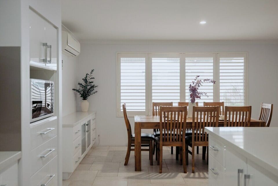 This spacious dining zone offers a scenic outlook to the patio, natural light, and cozy seating for eight—ideal for indoor-outdoor living.