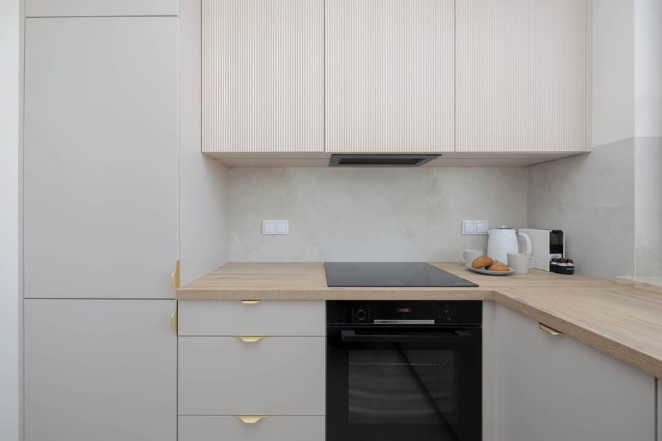 A centered view of an oven and stovetop built into light-colored cabinetry.