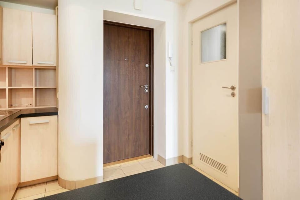 Small hallway with a wooden door and coat storage space. The hallway is simple, providing a functional entrance area.