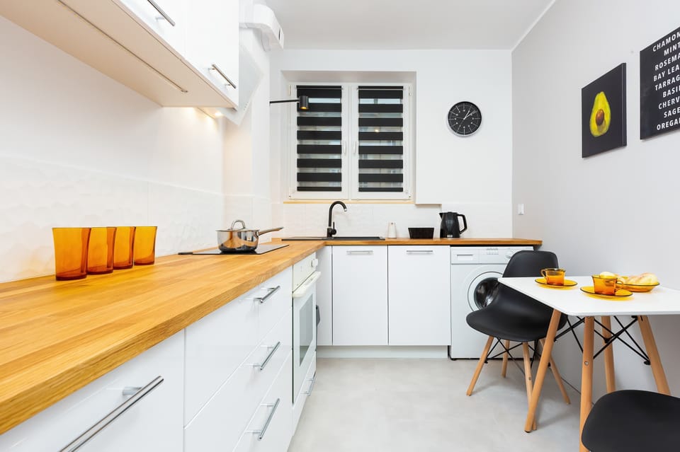 Functional kitchen with white furniture and wooden worktop. There is a table and chairs underneath the hay.