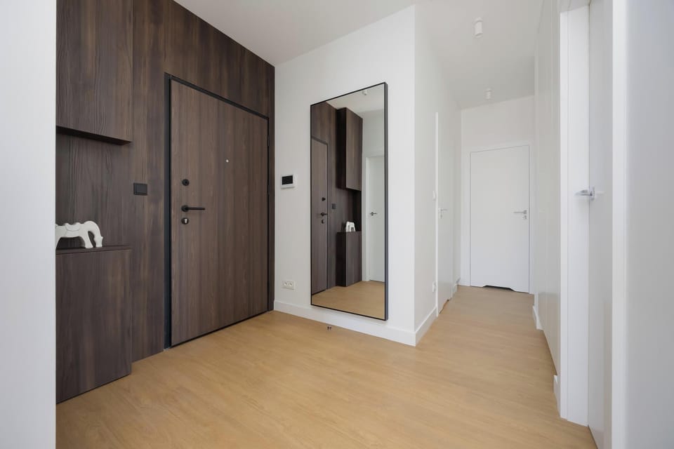 A hallway with wood floors and a dark entry door, offering access to the main rooms and creating a warm entrance.
