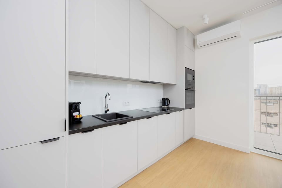 A sleek, modern kitchen with white cabinets, black appliances, and an open layout.