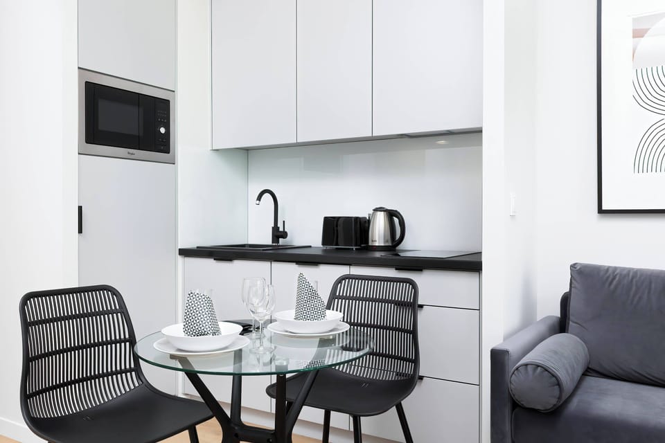 A small, functional kitchenette with minimalist cabinets and a dining table.