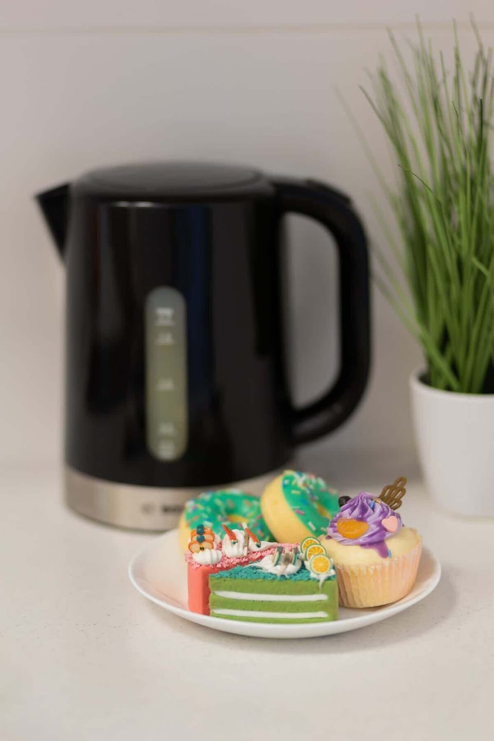 A compact kettle setup with mugs and a decorative plant, adding convenience and charm.

