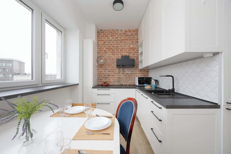 Another angle of the same modern kitchen, showcasing the glossy white cabinets and brick backsplash. A clean and stylish cooking space.