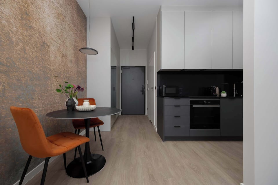 A modern open-concept kitchen and living area with sleek black cabinets. The kitchen is fully equipped with built-in appliances.