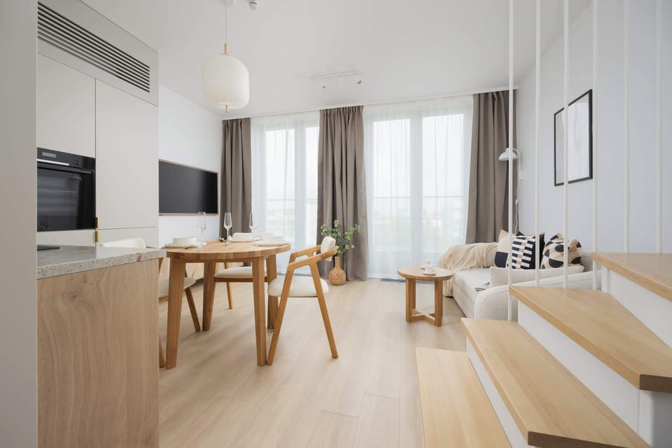 A spacious living room connected to the kitchen and dining area. The wooden dining table stands out as the central point of the room.
