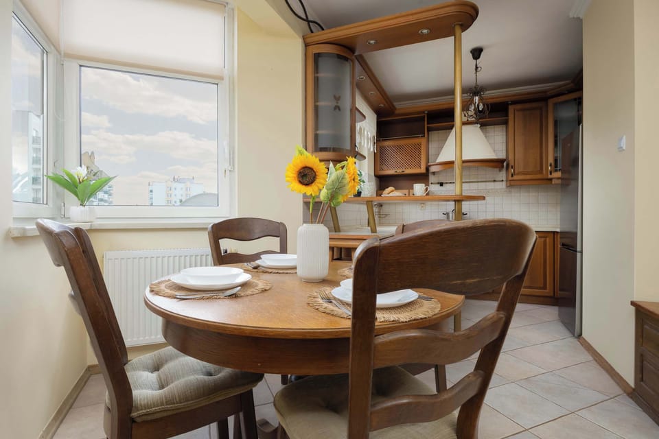 A warm and traditional kitchen with wooden cabinetry and a dining nook. A window provides natural light for morning meals.