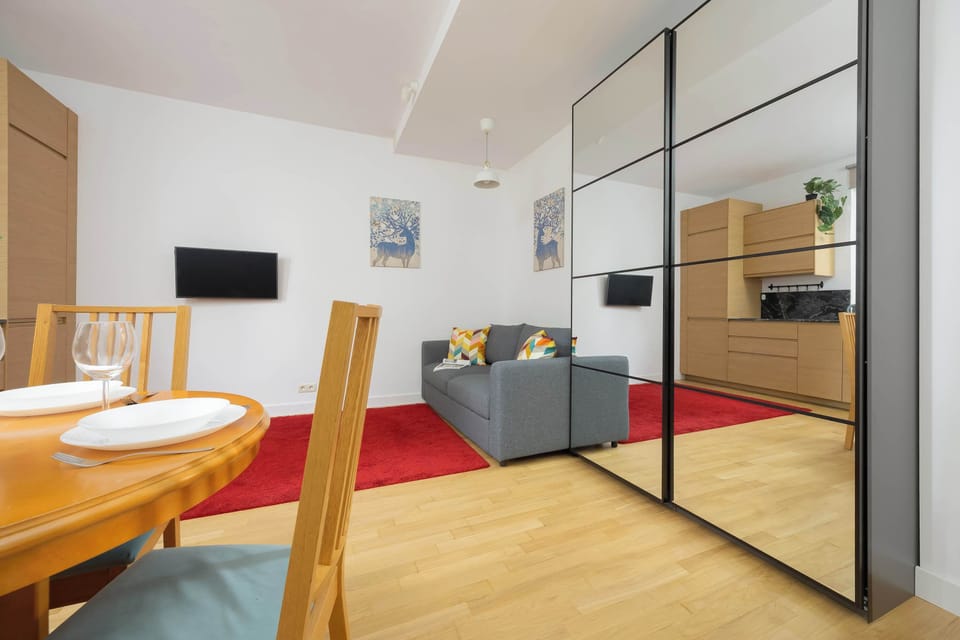 An open-plan view of the living and dining space, with a mirrored closet and a pop of red from the rug.