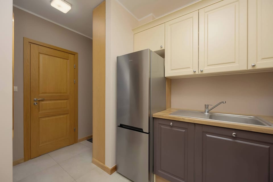 A modern kitchenette with cream and dark brown cabinets, equipped with essential appliances.