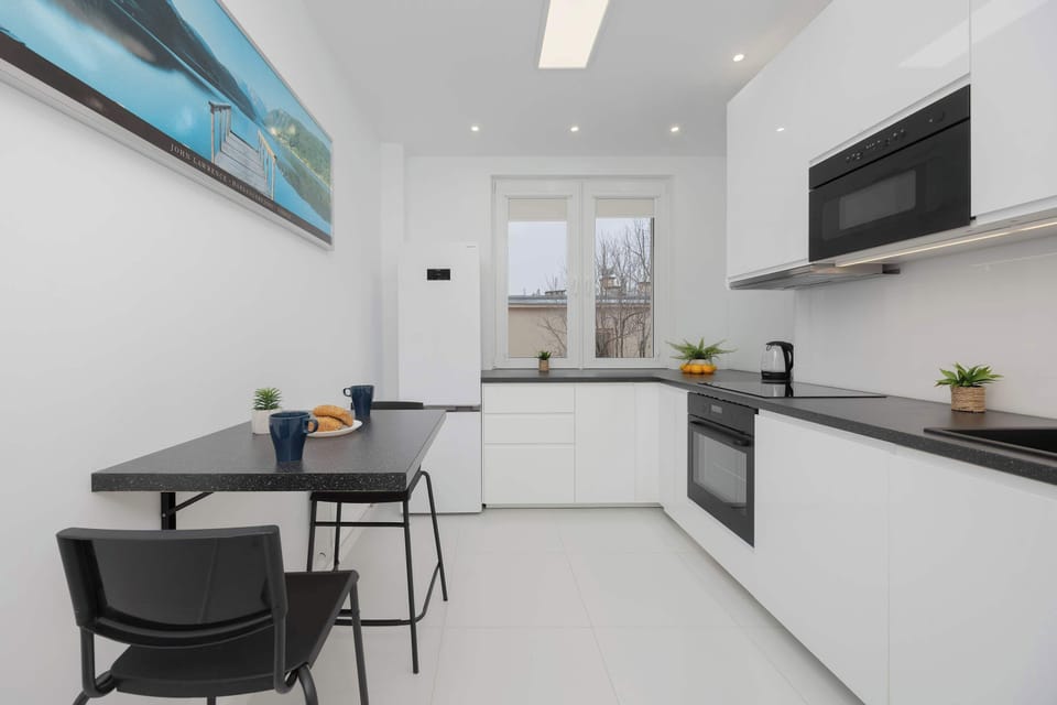 A sleek, contemporary kitchen with white cabinetry, black countertops, and a clean, modern design.