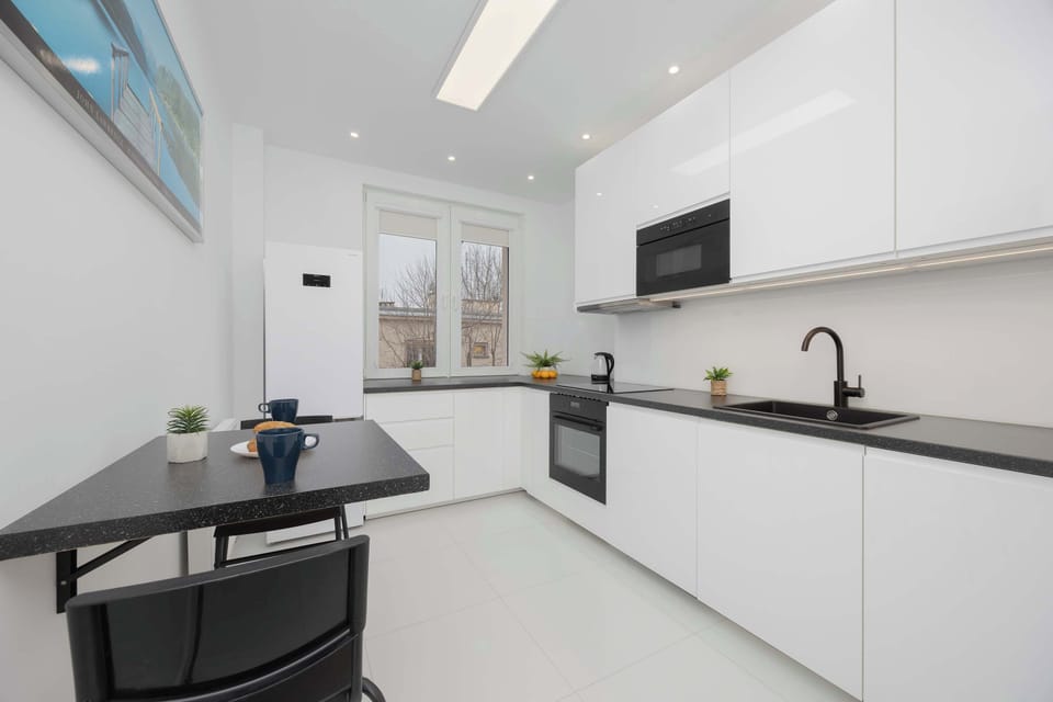 A sleek, contemporary kitchen with white cabinetry, black countertops, and a clean, modern design.