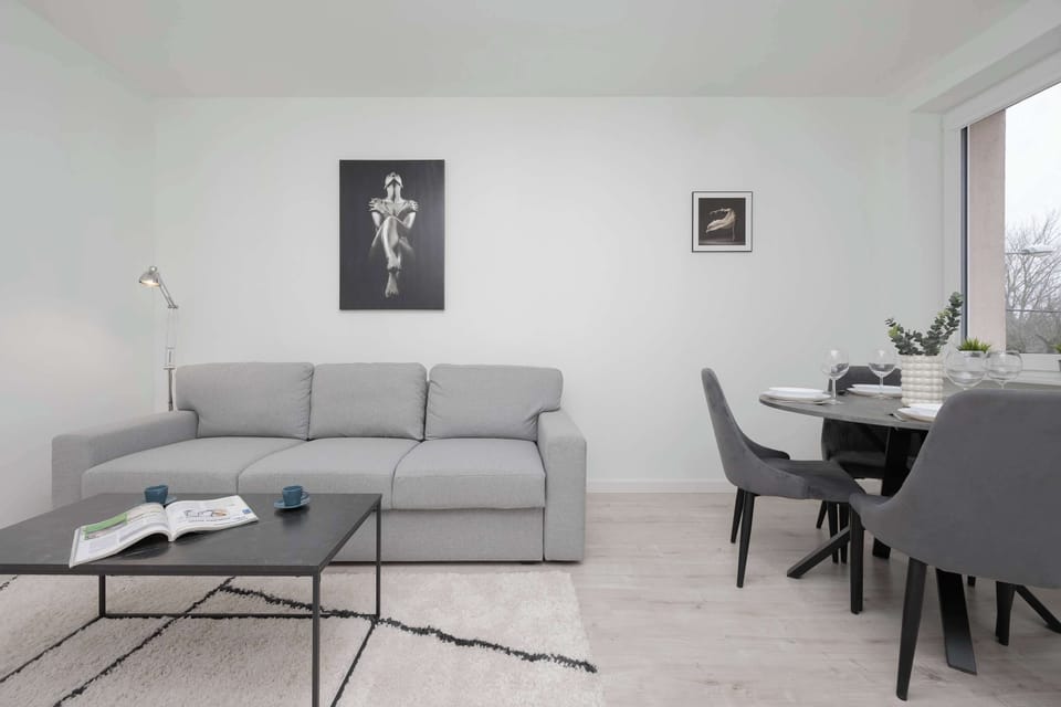A bright and spacious living room with a modern gray sofa, a stylish coffee table, and minimalistic decor.