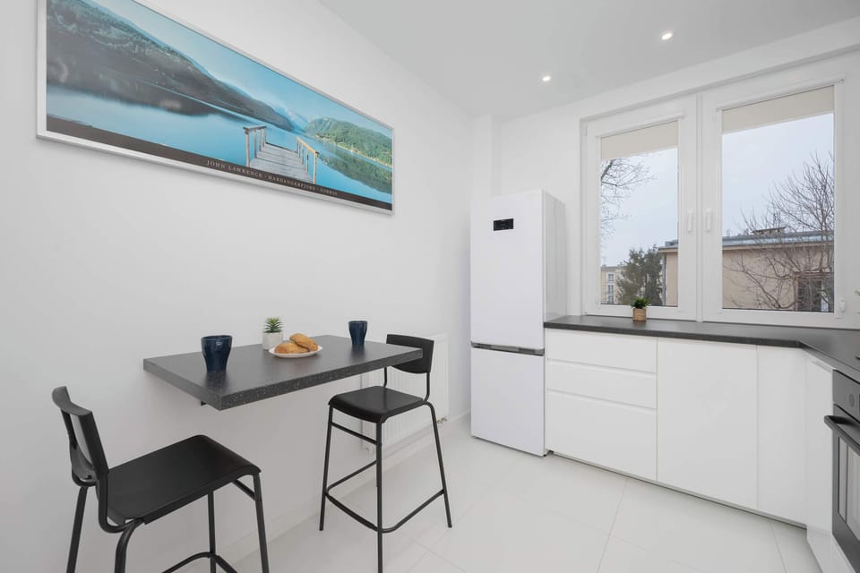 A sleek, contemporary kitchen with white cabinetry, black countertops, and a clean, modern design.
